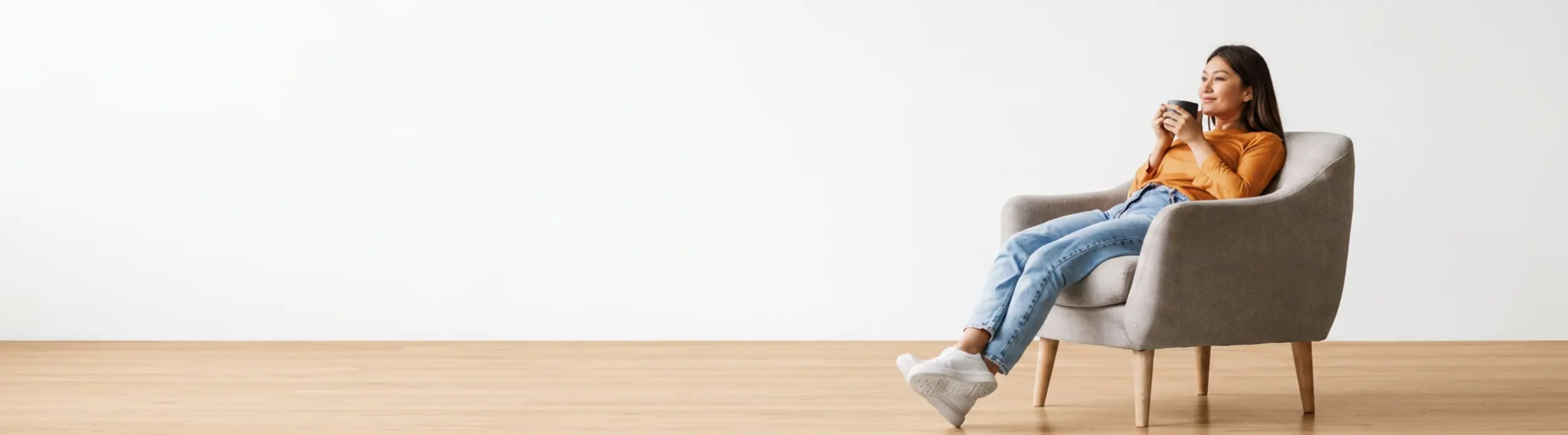 Relaxed asian woman drinking coffee on a couch