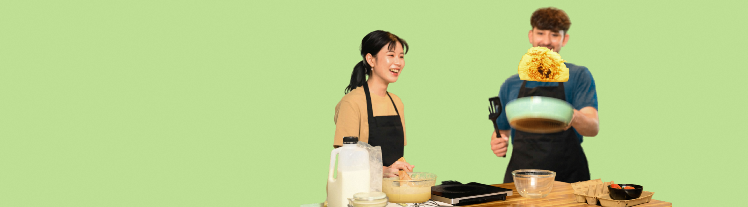 Playful couple flipping pancake and sharing laughter in kitchen