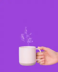 Hand holding cup of coffee on purple background