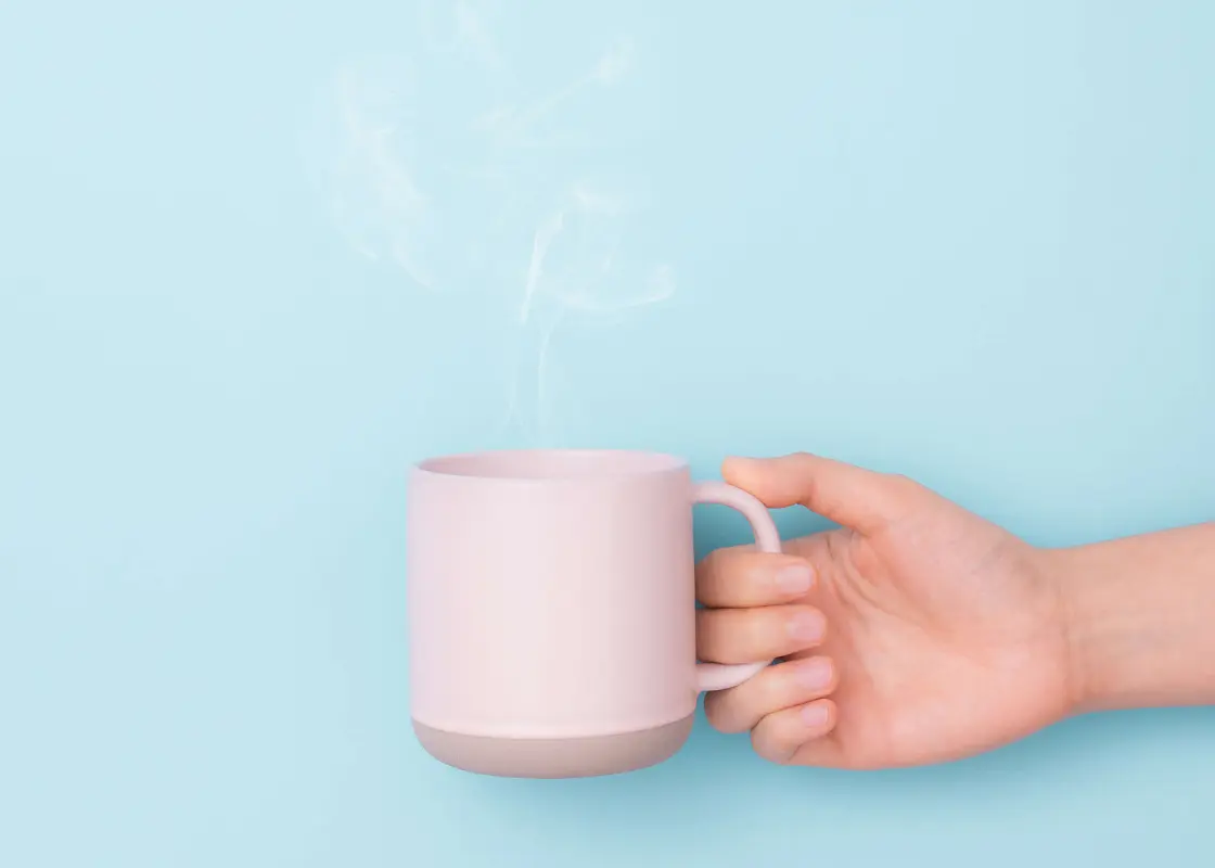 Hand holding cup of coffee on purple background