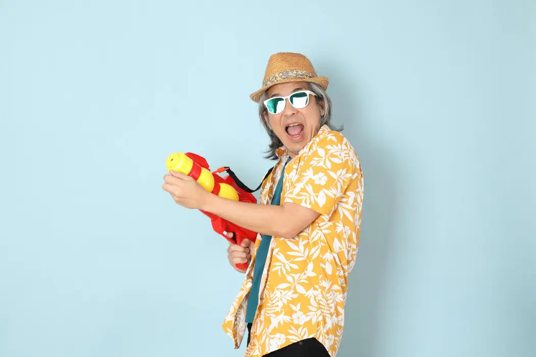 Senior asian man wearing summer clothes holding water gun